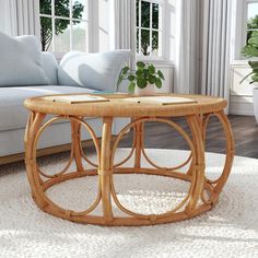 a wicker coffee table in front of a couch and window with potted plants on it