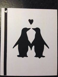 two penguins are standing next to each other with a heart in their beaks on top of them