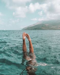 a person floating in the ocean with their feet up above the water's surface