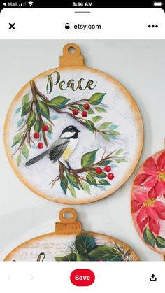 three christmas ornaments are hanging on the wall, one has a bird and holly wreath