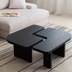 two black tables sitting on top of a rug in front of a couch and table