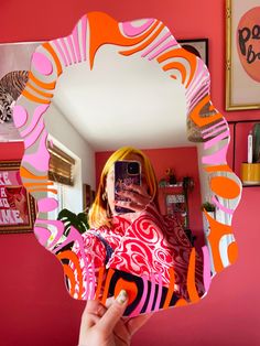 a woman taking a selfie in front of a mirror with an orange and pink design on it