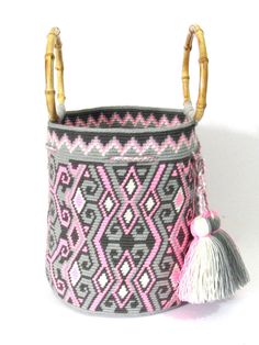 a pink and grey basket with bamboo handles