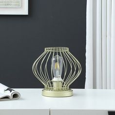 a white table with a lamp on top of it and a book next to it