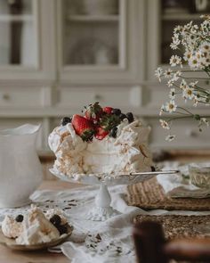 a cake sitting on top of a table next to a vase filled with strawberries