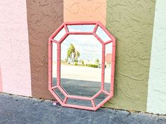 a pink mirror sitting on the side of a building