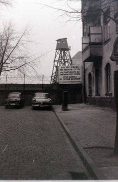 two cars are parked in front of an old building with a water tower on top