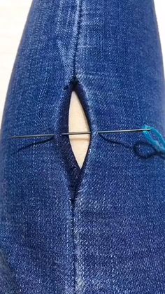 a pair of blue jeans being sewn together with a sewing needle in the middle