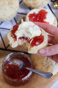 someone is holding up a biscuit with cream cheese and strawberry jam on the top