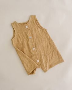 a tan top with buttons on the front and back, sitting on a white surface