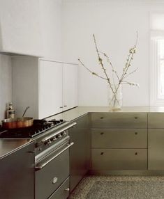 a kitchen with stainless steel appliances and counter tops, along with a vase filled with flowers