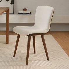 a white chair sitting on top of a rug next to a wooden table and desk