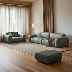 a living room with two couches and a ottoman in front of a large window