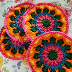 three crocheted coasters sitting on top of a flowery tablecloth covered table