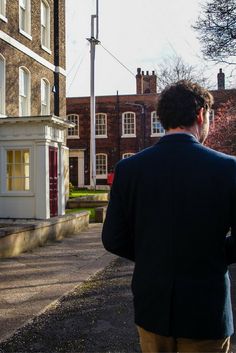 a man is walking down the street with his back to the camera as he looks at an old building