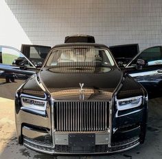 the front end of a black rolls royce parked next to other cars