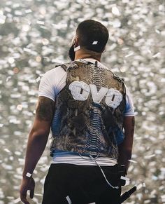 a man wearing a vest and headphones standing in front of confetti falling from the sky