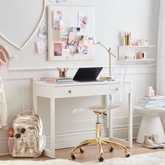 a white desk with a laptop on top of it next to a chair and other items