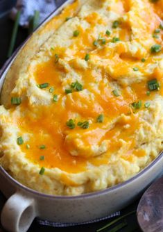 a casserole dish with mashed potatoes and green onions on the side, ready to be eaten