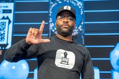 a man wearing glasses and a black shirt is making the peace sign with his hands