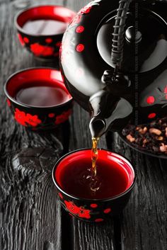 tea being poured into red cups on wooden table