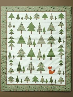 a quilted wall hanging with green trees and a red fox on the bottom half