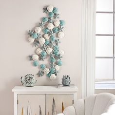 a white chair sitting in front of a wall hanging with crocheted balls on it