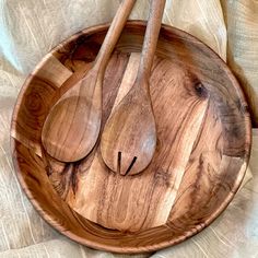 two wooden spoons in a bowl on a bed