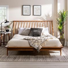 a bed sitting in a bedroom next to two potted plants on top of a table