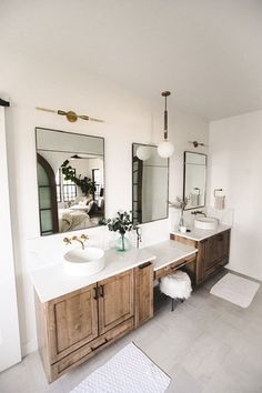 a bathroom with two sinks, mirrors and rugs on the floor in front of them