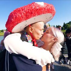 a man and woman kissing each other in front of a group of people wearing costumes