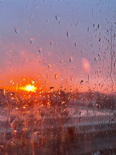 the sun is setting through some rain covered windshields as seen from inside an airplane