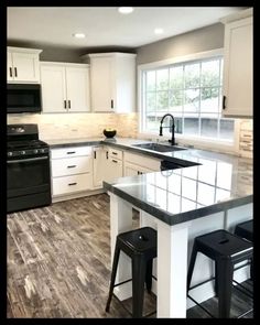 a kitchen with white cabinets, black appliances and counter tops in the middle of it