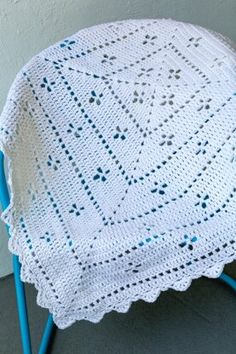 a white crocheted blanket sitting on top of a blue chair