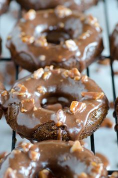 there are many chocolate donuts with nuts on top of the doughnuts is sitting on a cooling rack