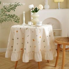 a table with flowers and vases on it next to a chair in a room