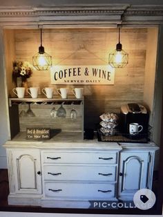 a coffee and wine bar with lights on the wall next to an open cabinet filled with cups