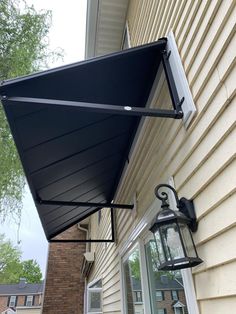 a black awning hanging from the side of a house next to a lamp post