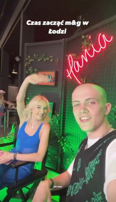 a man and woman sitting next to each other in front of a neon green wall