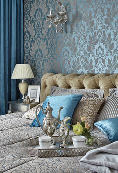 a bed with blue and silver decor in a bedroom next to a chandelier