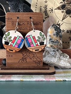 wooden earrings with colorful designs on them sitting on a stand next to rocks and other items