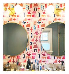 a bathroom with two round mirrors and colorful wallpaper