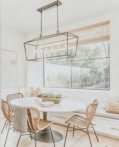 a dining room table with four chairs and a bench in front of a large window