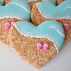 three heart shaped cookies decorated with frosting and sprinkles on a white surface