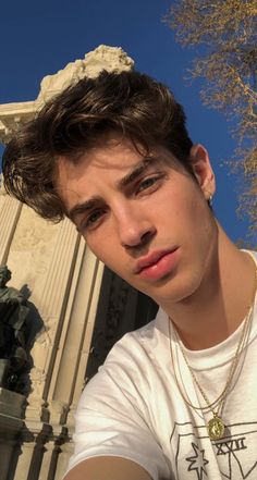 a young man is posing in front of a building