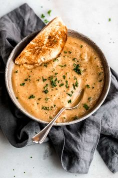 a bowl filled with soup and a piece of bread sticking out of it's side