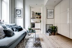 a living room filled with furniture next to a window and wooden flooring covered in white walls