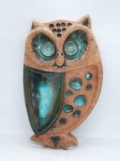 an owl statue is sitting on a white surface and it has blue eyes, with one eye open