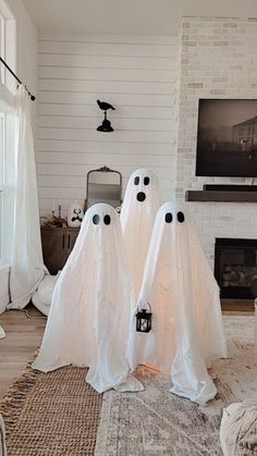 two white ghost statues sitting in front of a tv on a wall above a fireplace