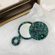 a pair of green marbled mirrors sitting on top of a white sheet next to a gold framed mirror